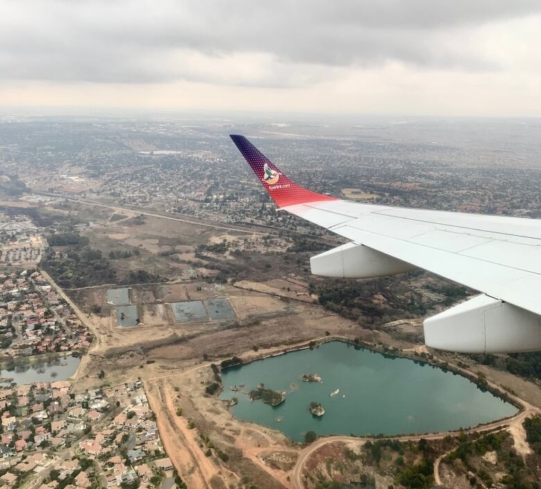 View from cabin of plane flying from South Africa to Zambia. Shot is looking over the wing at the landscape and some ponds.