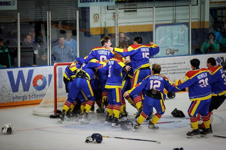 Hockey players pile onto their goalie.