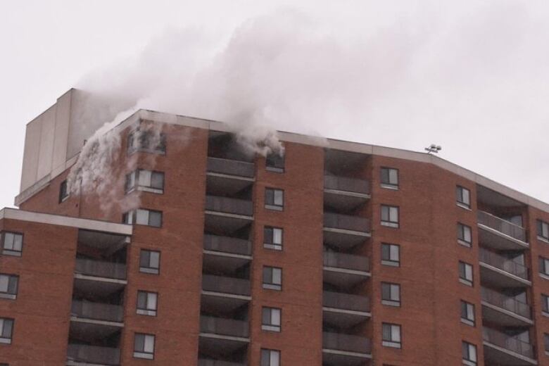 Smoke billows out several windows on the top floor of a hotel.