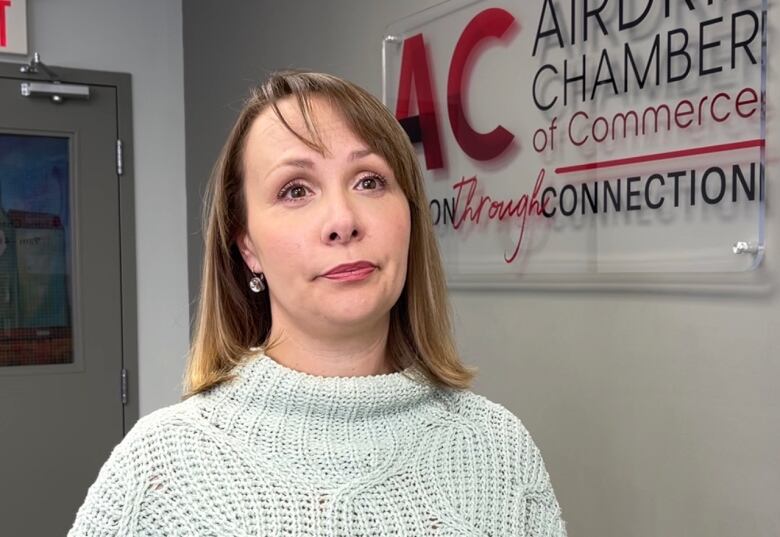 Marilyne Aalhus stands in front of a sign at Airdries Chamber of Commerce.