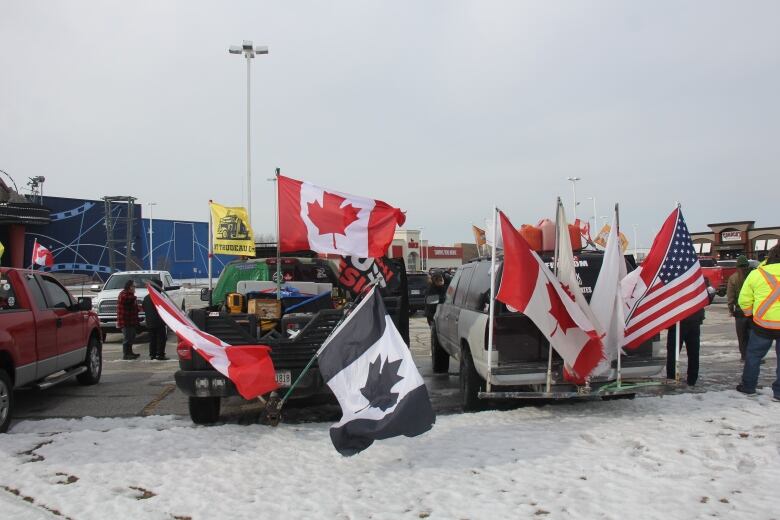 Parked trucks with Canadian and American flags waving from the back of the trucks