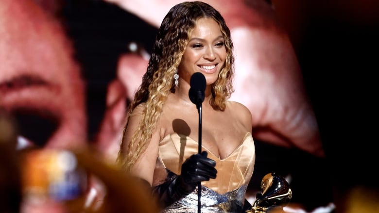 A smiling woman stands in front of a microphone. 