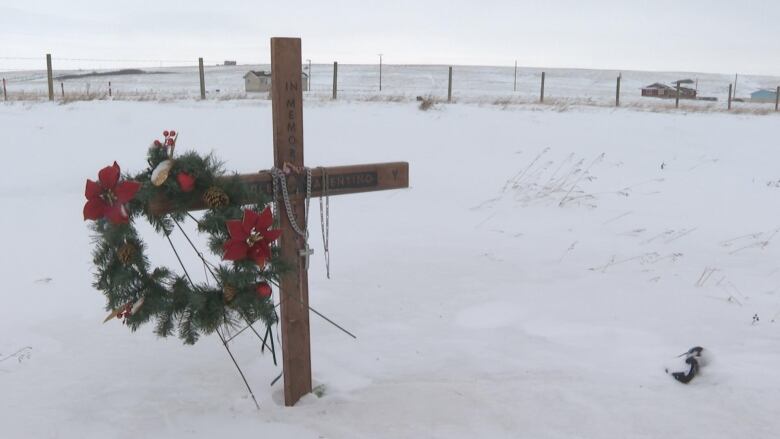 A cross in the snow on the side of a highway.