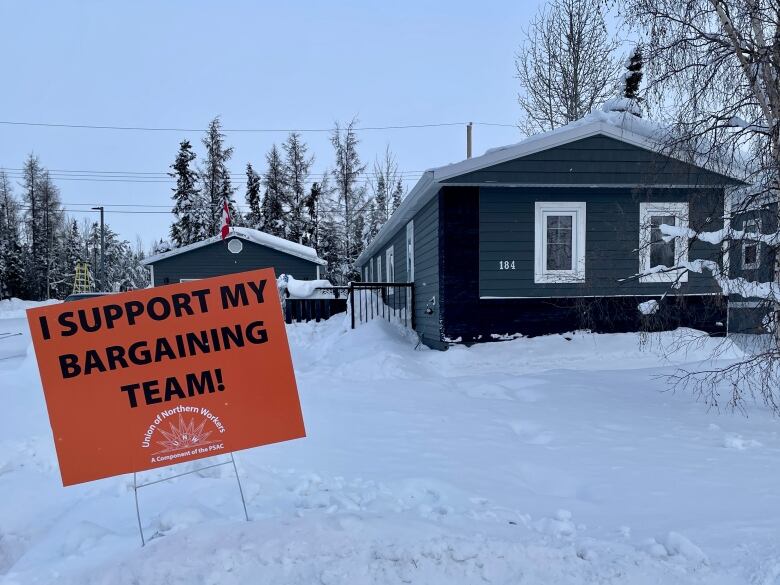 An orange sign on a lawn reads: 