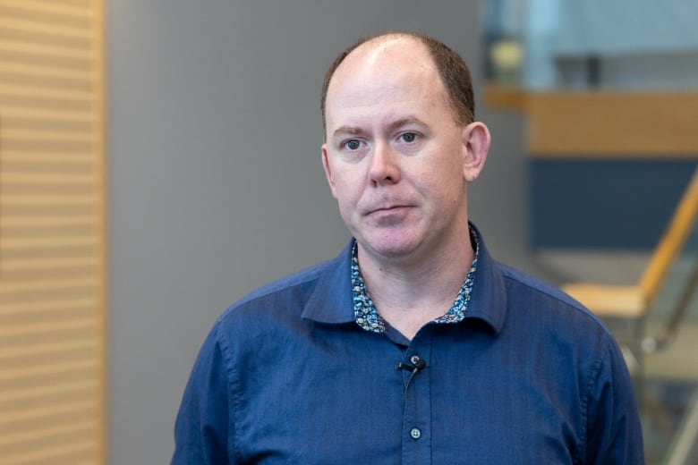 Headshot of a man in a blue shirt.