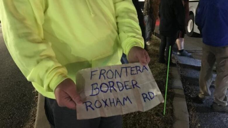 Hands holding a sign that reads 