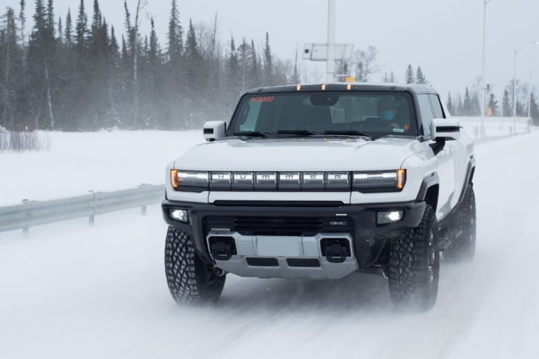 A man driving a large white vehicle in the snow.