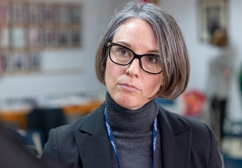 A woman with glasses and short dark hair listens to a question.