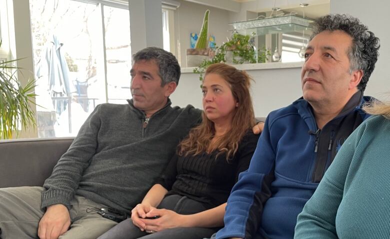 Four people sit on a couch and look off camera.