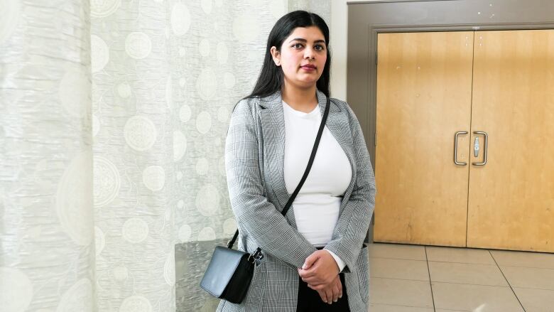 A woman, Simran Sharma, stands in a hallway and poses for a photo.