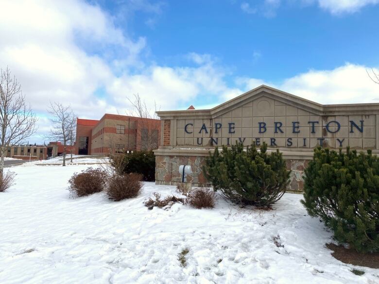 A sign saying Cape Breton University sits in front of a brick building.