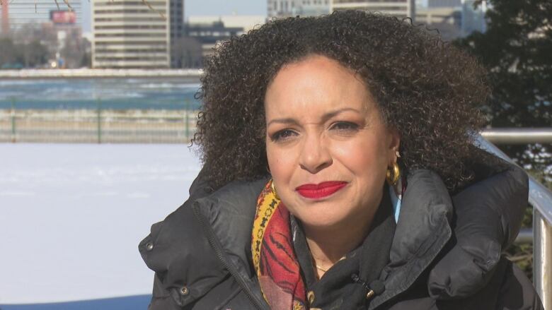 Camille Armour sits outside in front of the Detroit River.