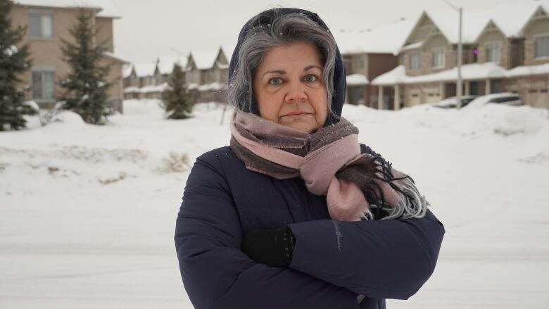 A woman crosses her arms outside in the snow.