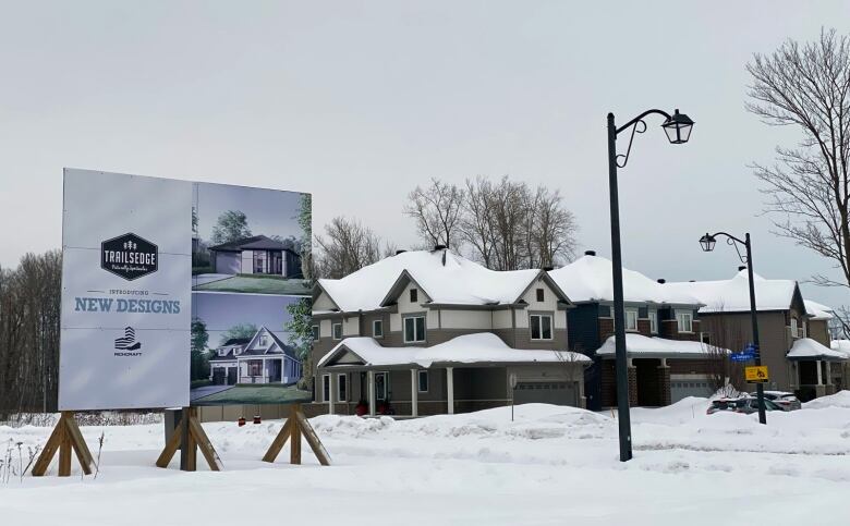 A sign advertises new build homes on a residential street.