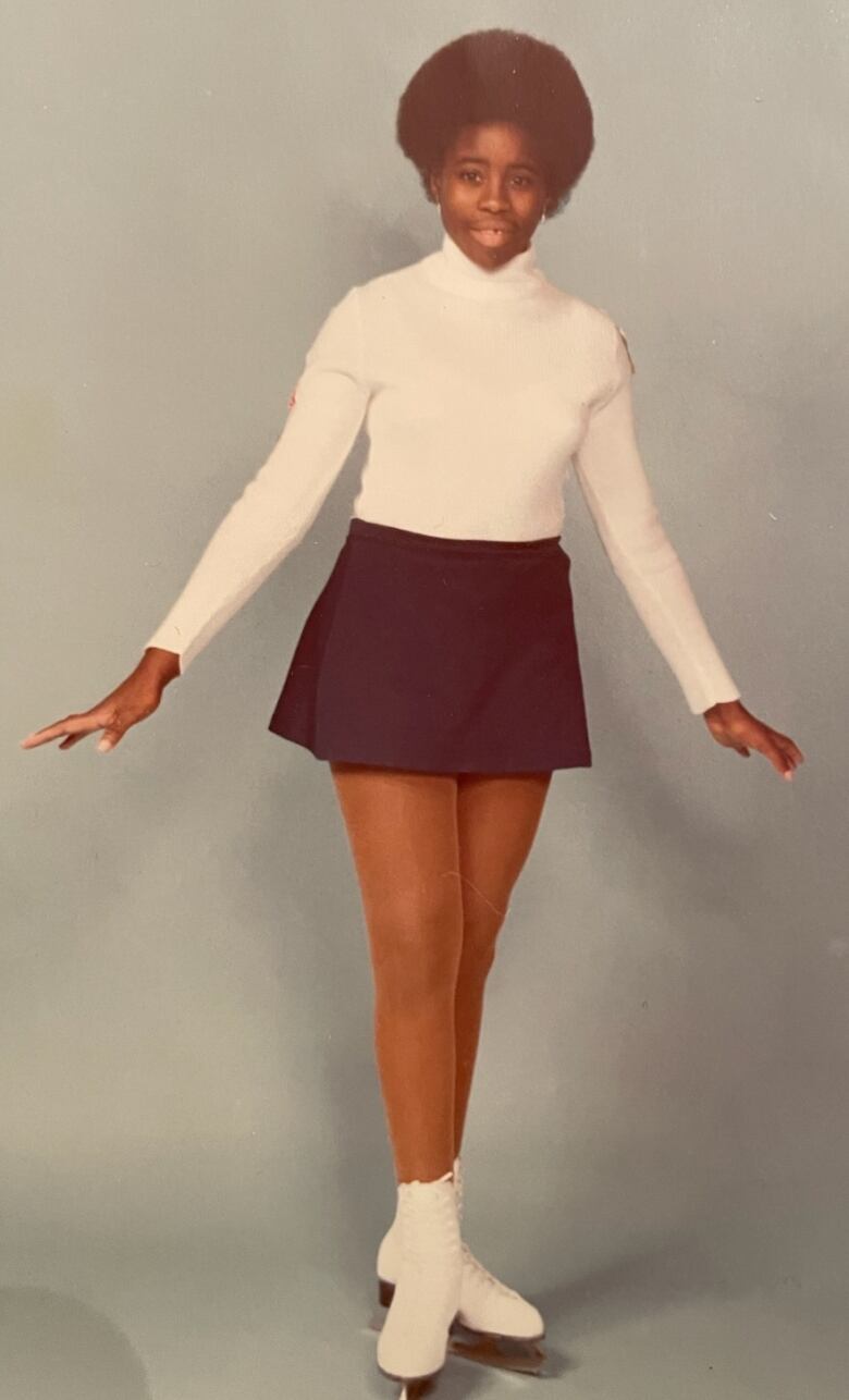 A 14-year-old Black girl poses on figure skates.