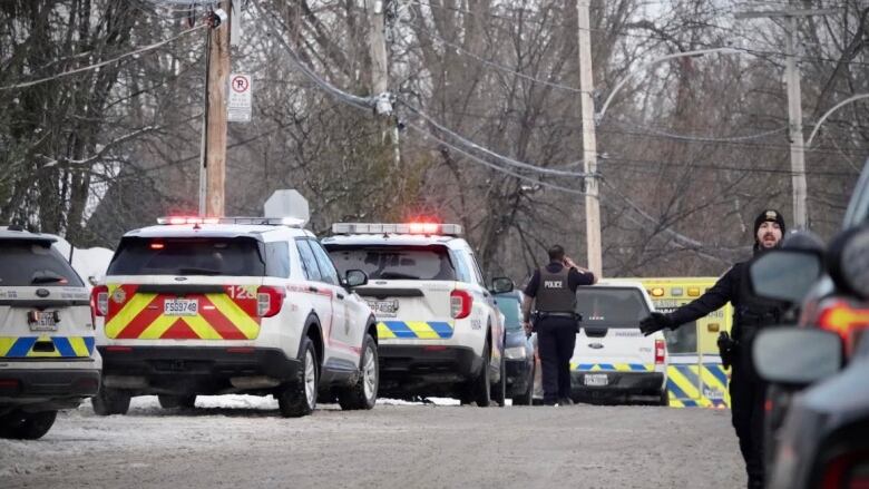 Officers walk between Laval police cars outside a daycare.