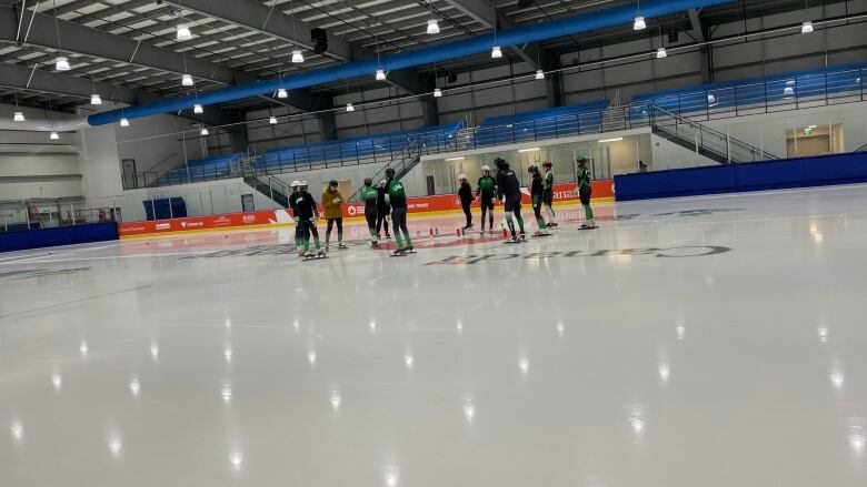 Short track speed skaters on the ice in a large arena. 