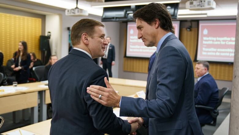 Two men shaking hands inside of a boardroom. 