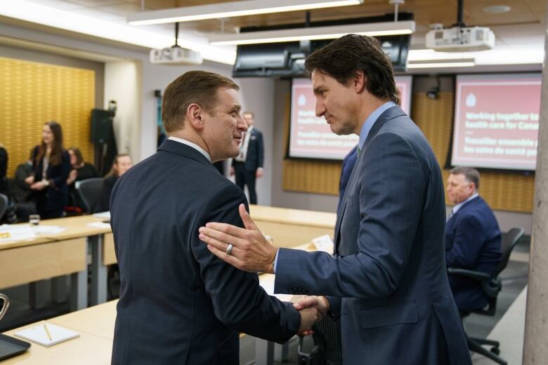 Two men shaking hands inside of a boardroom. 