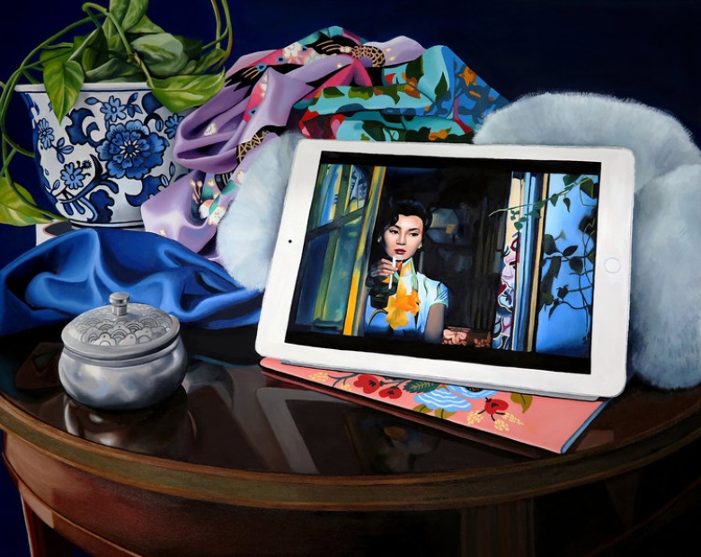 A still life oil painting depicting a polished round brown table that's been topped by a cluttered assemblage of objects. Visible is a blue and white planter filled with a pothos, a crumpled patterned robe in an Asian style, indistinguishable furry forms, an ornately patterned silver canister and an iPad propped up to show a frame from the movie In the Mood for Love.