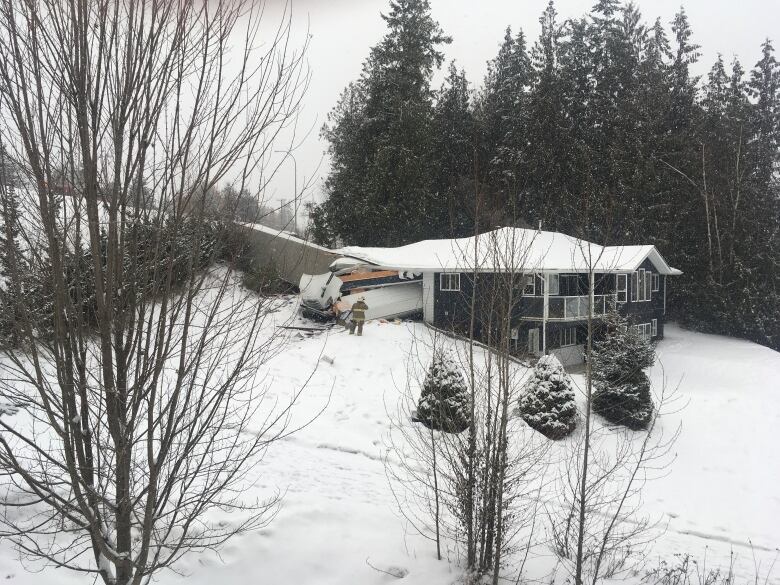 A firefighter stands outside a home where a truck has driven through