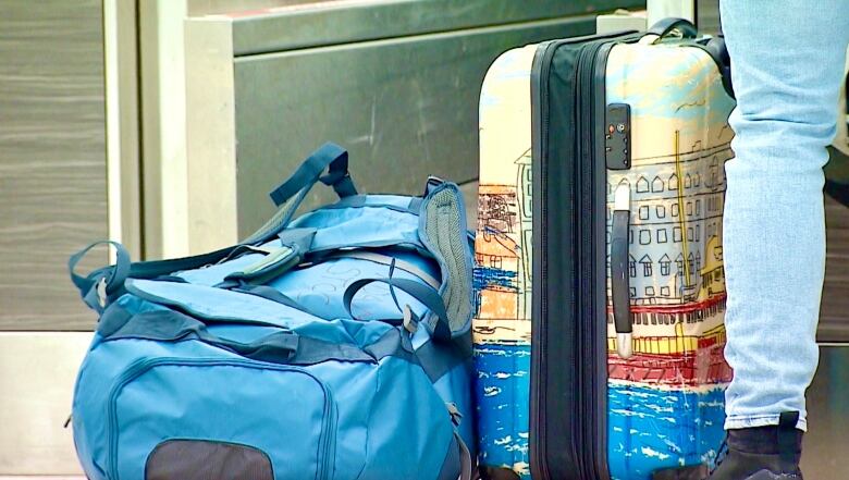 A suitcase and backpack are on the floor at an airport check-in counter.