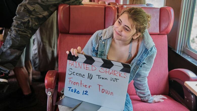 A young woman holds a clapperboard during the filming of Painted Sharks.