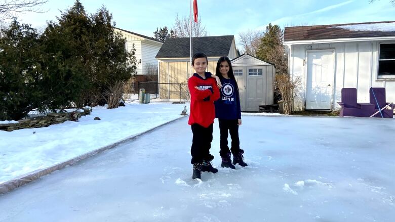 Jaxon and Alexandra Borromeo stand on their slushy backyard rink in London, Ont., on February 8, 2023. 