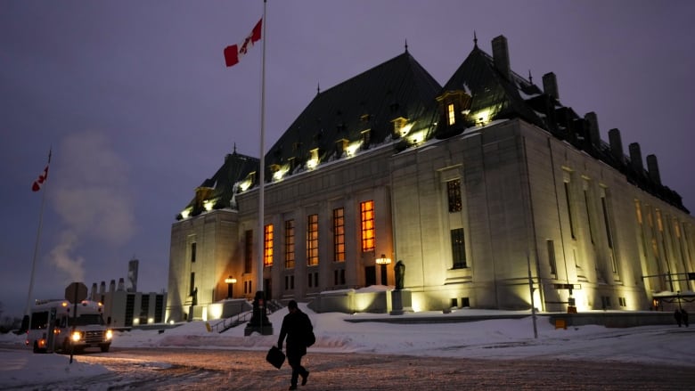 A person crosses a snow-covered street near the Supreme Court of Canada building in Ottawa.