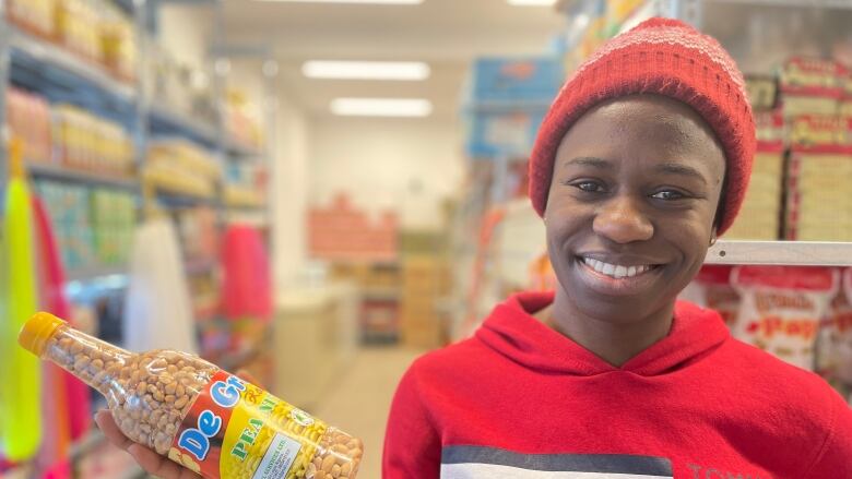 A Black woman in a red sweater holds peanut box.