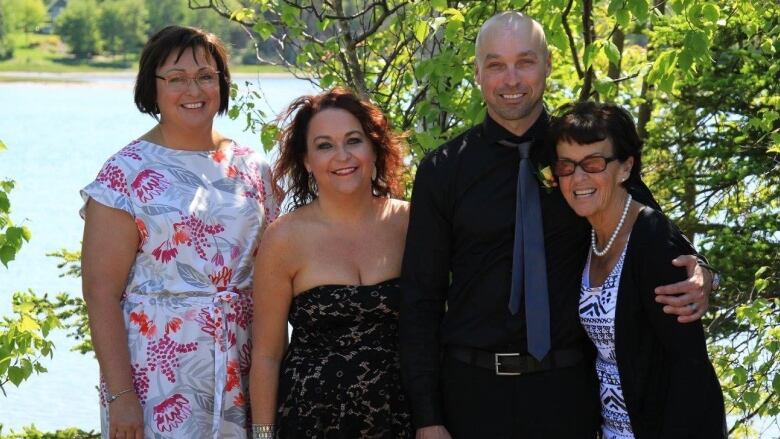 A mother, her son, and her two daughters pose for a photograph in front of the water.