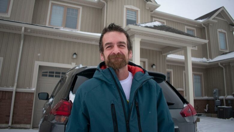 A man smiling in front of a house.