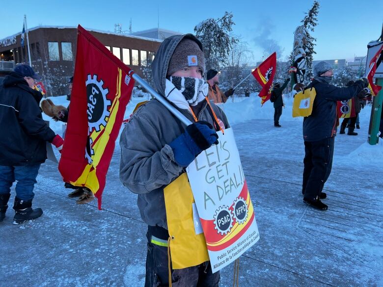 Bundled up person with yellow sign.