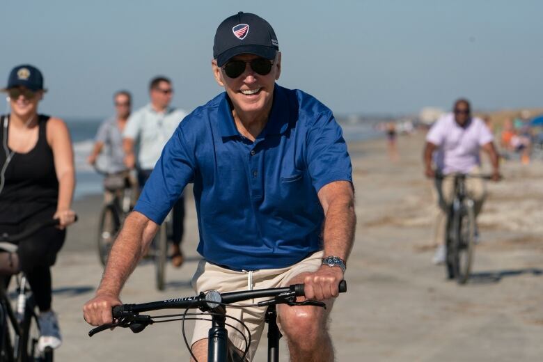 U.S. President Joe Biden is seen riding a bicycle along a stretch of beach in South Carolina in August 2022.