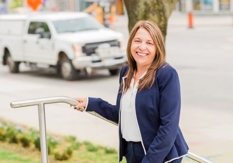 Enza Alexander, vice-president with cybersecurity firm ISA, is shown outside holding a handrail on a set of stairs.