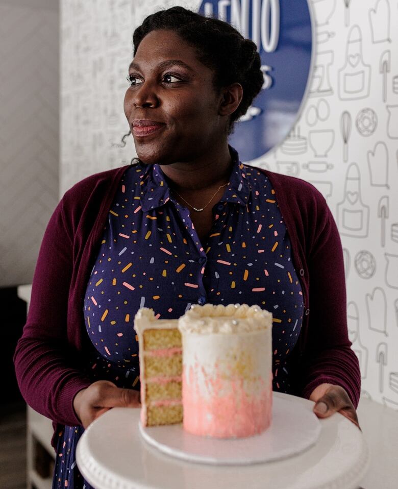 Lenore Johnson holds a vanilla cake with pink and white frosting