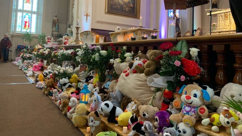 Stuffed toys and flowers line the bottom of a church altar. 