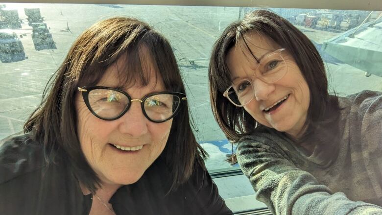 Two women with brown hair and glasses smiling in a selfie.