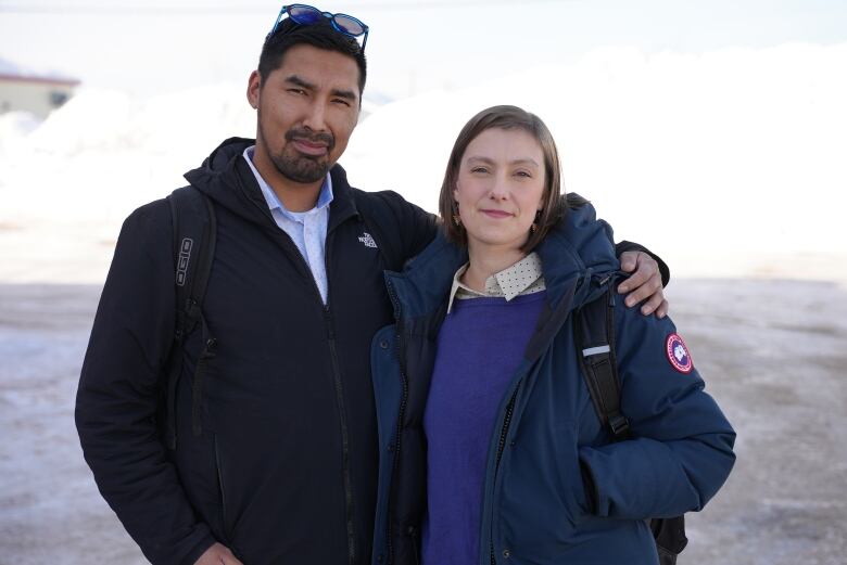 Two people standing outside, one with his arm around the other.