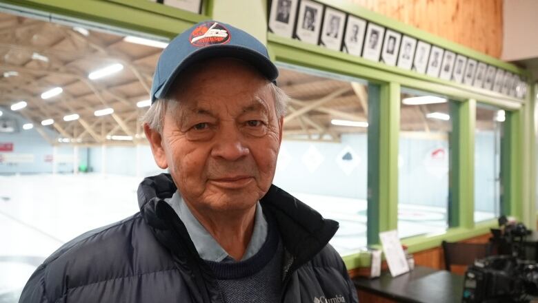 Norman Meade, founder of the Aboriginal Curling League of Winnipeg, poses in front of the ice sheets.