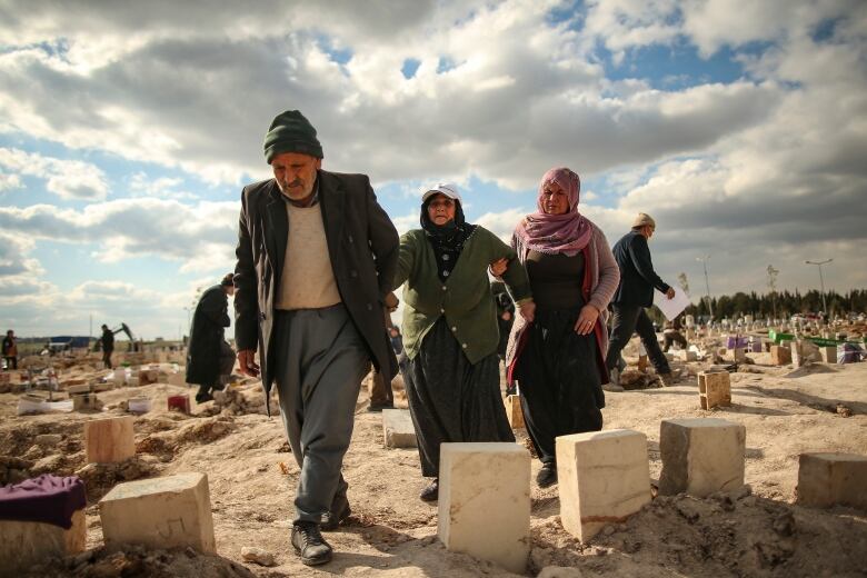 Three people walk through a cemetery in Turkey