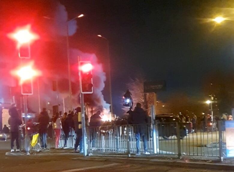 Smoke billows outside a building as onlookers watch from nearby.