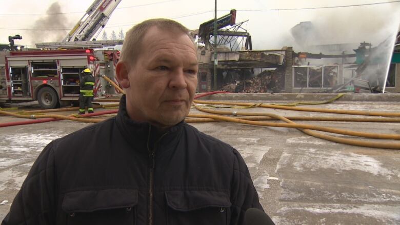 A man stands on Main Street in Winnipeg following a fire.