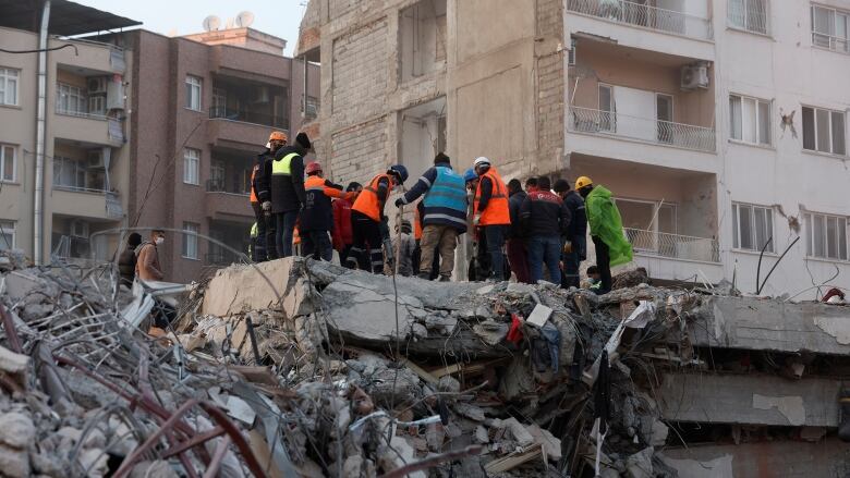 Rescue workers at the site of a collapsed building, days after a powerful earthquake, in Iskenderun, Turkey.