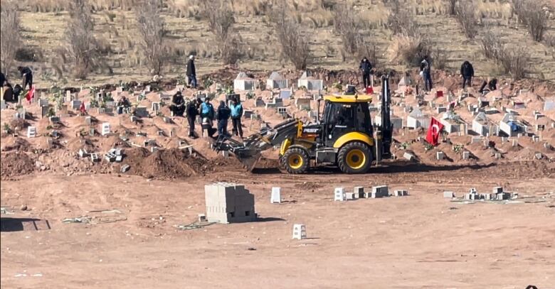 A small backhoe is used to dig holes in a cemetery.