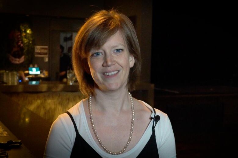 A white woman smiles in a nightclub.