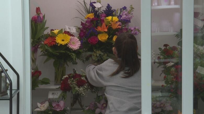 a woman arranges colourful bouquets of flowers 