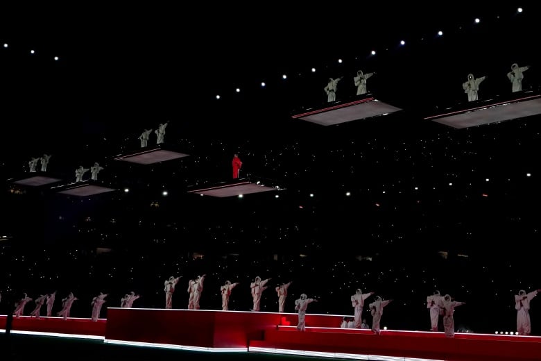 People stand on floating platforms suspended at different heights over a stadium field.