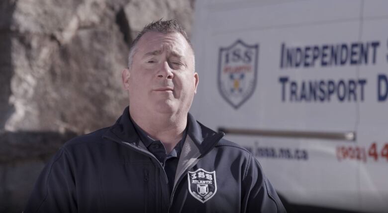 A man stands in front of a company van looking into the camera. 