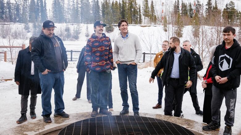 A group of people gather outside around a fire pit.